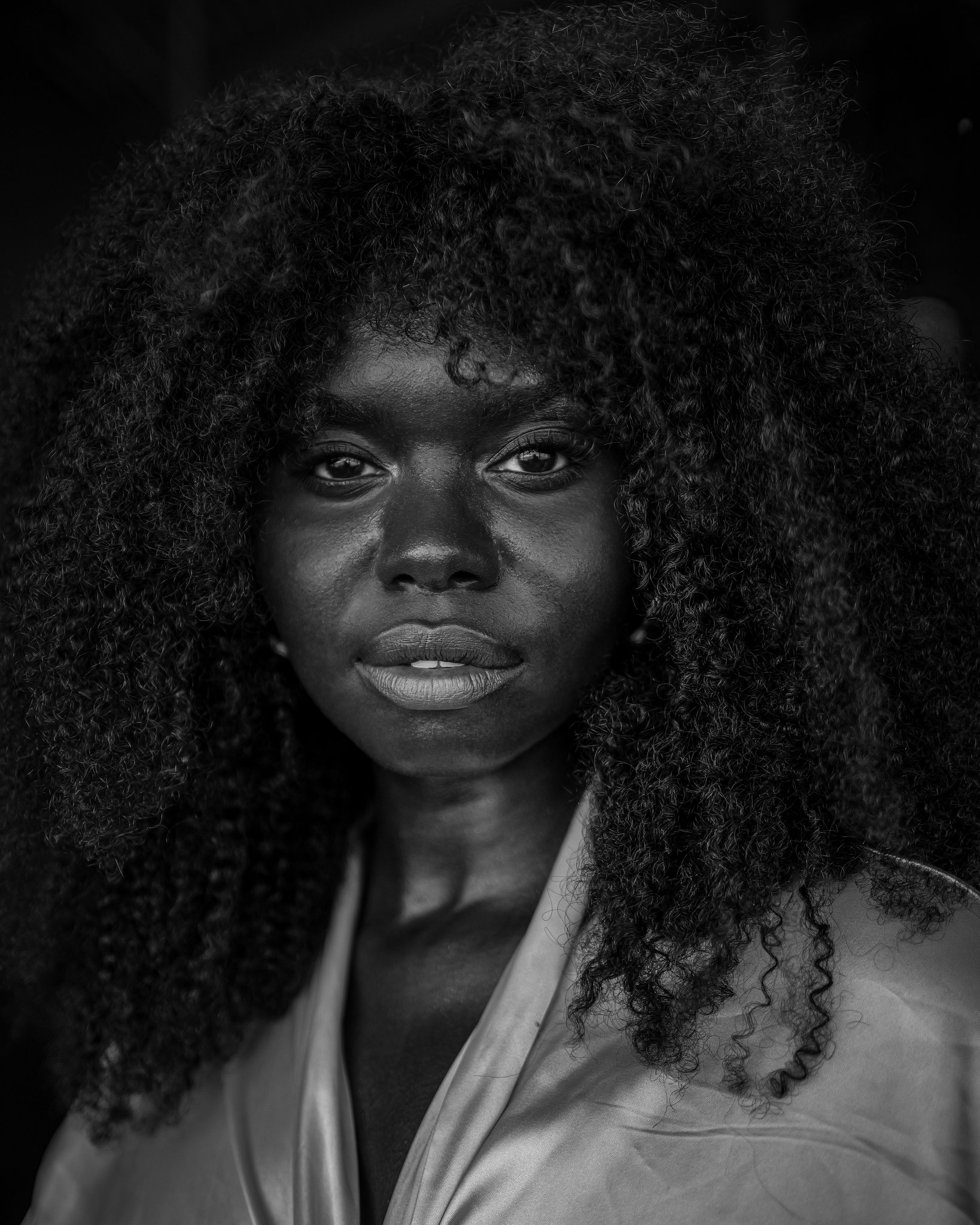 Close portrait of a woman with full curly hair, looking directly at the camera